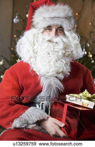 Father christmas / santa Claus holding a pile of presents View Large Photo Image Stock Photo - Father christmas / santa Claus holding a pile of presents. Fotosearch