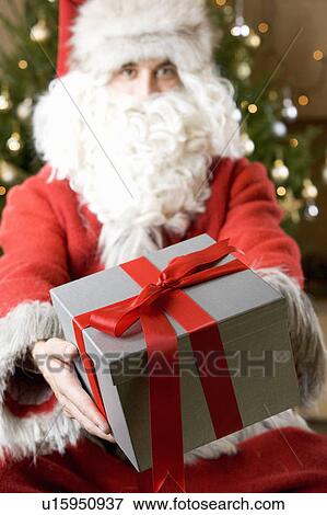 Father christmas / santa Claus holding a present View Large Photo Image Stock Photo - Father christmas / santa Claus holding a present. Fotosearch