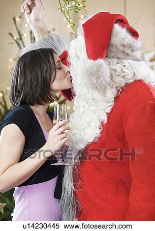Stock Photography - Santa Claus kissing a woman under the mistletoe. Fotosearch