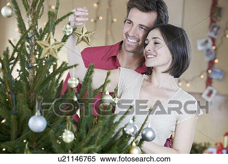 Stock Photography - A couple decorating the Christmas tree. Fotosearch