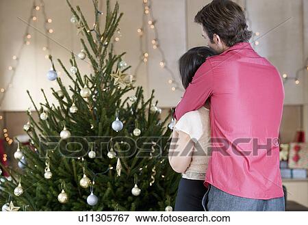 A couple standing by the Christmas tree View Large Photo Image Stock Photo - A couple standing by the Christmas tree. Fotosearch