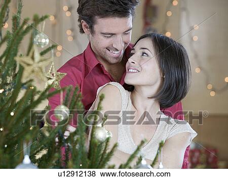 A couple standing by the Christmas tree View Large Photo Image Stock Photo - A couple standing by the Christmas tree. Fotosearch