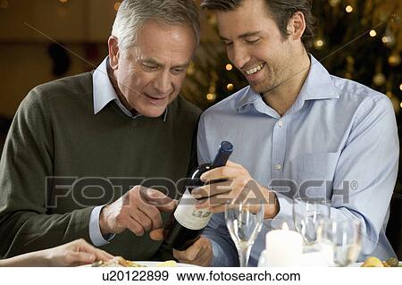 Stock Photo - A father and son looking at a wine bottle. Fotosearch