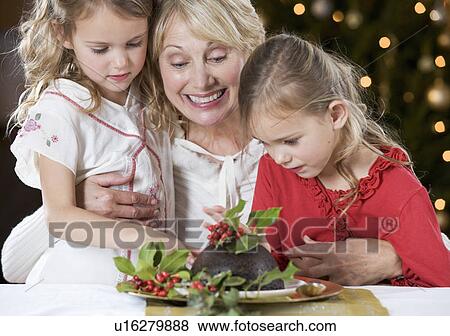 A grandmother and her granddaughters looking at a Christmas pudding View Large Photo Image Stock Photo - A grandmother and her granddaughters looking at a Christmas pudding. Fotosearch