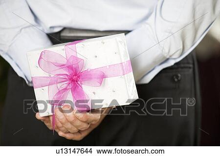 Picture - A man holding a surprise gift. Fotosearch