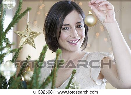 A woman decorating a Christmas tree View Large Photo Image Stock Image - A woman decorating a Christmas tree. Fotosearch