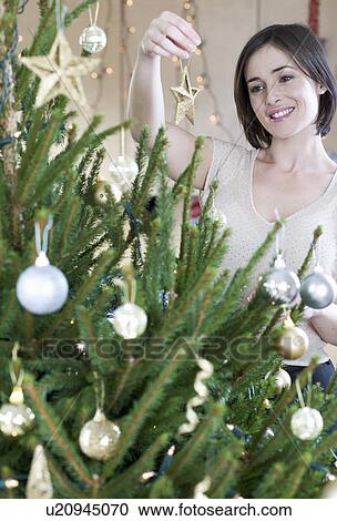 Stock Image - A woman decorating a Christmas tree. Fotosearch