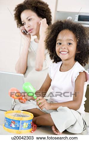 Little girl playing toy drum while mother tries to talk on the telephone View Large Photo Image Stock Image - Little girl playing toy drum while mother tries to talk on the telephone. Fotosearch