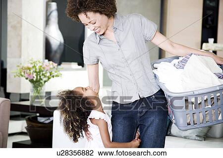 Stock Image - Mother and young daughter doing the washing at home. Fotosearch