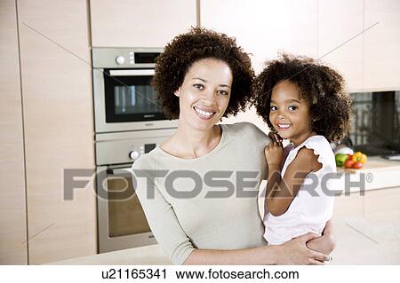 Mother holding young daughter at home, smiling View Large Photo Image Stock Image - Mother holding young daughter at home, smiling. Fotosearch