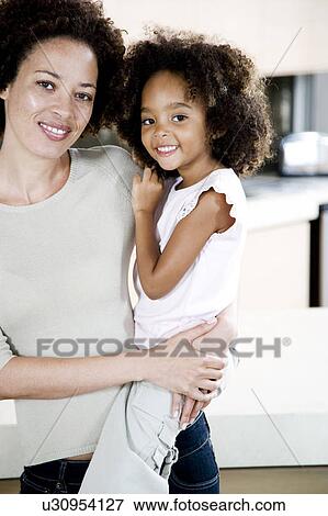 Mother holding young daughter at home, smiling View Large Photo Image Stock Photo - Mother holding young daughter at home, smiling. Fotosearch