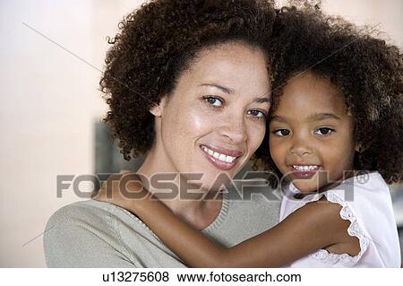 Stock Photo - Mother holding young daughter, smiling. Fotosearch