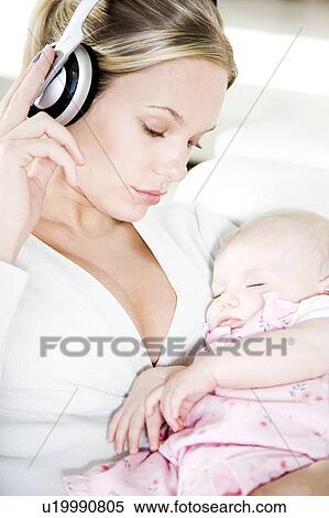 Mother listening to music on headphones while baby sleeps View Large Photo Image Stock Photography - Mother listening to music on headphones while baby sleeps. Fotosearch
