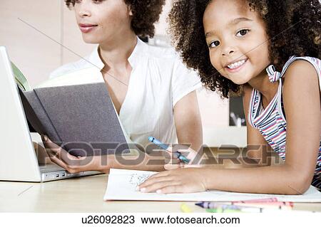 Mother reading and working at a laptop while young daughter plays View Large Photo Image Stock Image - Mother reading and working at a laptop while young daughter plays. Fotosearch