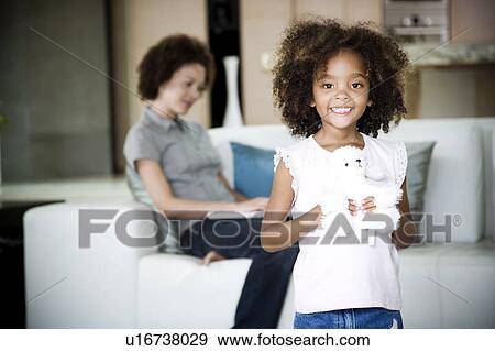 Mother reads while young daughter plays with her stuffed toy View Large Photo Image Stock Photo - Mother reads while young daughter plays with her stuffed toy. Fotosearch