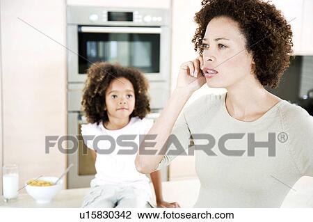 Mother talking on mobile phone, small daughter in background View Large Photo Image Stock Image - Mother talking on mobile phone, small daughter in background. Fotosearch
