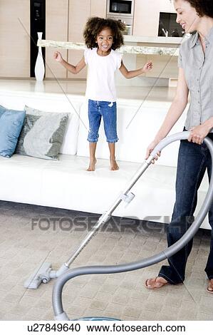 Mother vacuuming while young daughter watches View Large Photo Image Stock Image - Mother vacuuming while young daughter watches. Fotosearch