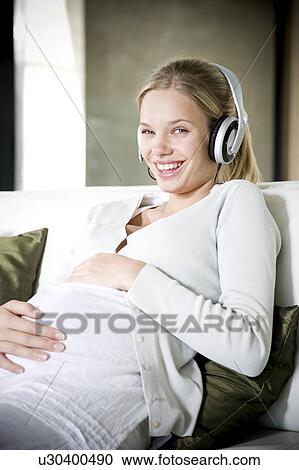 Pregnant woman laughing whilst listening to music on headphones View Large Photo Image Stock Image - Pregnant woman laughing whilst listening to music on headphones. Fotosearch