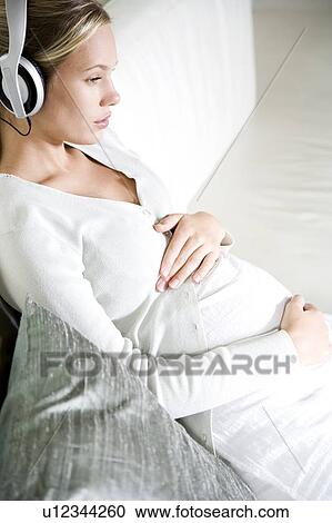 Pregnant woman relaxing whilst listening to music on headphones View Large Photo Image Stock Image - Pregnant woman relaxing whilst listening to music on headphones. Fotosearch