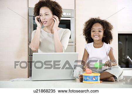 Stressed mother working from home while daughter plays a toy drum View Large Photo Image Stock Photography - Stressed mother working from home while daughter plays a toy drum. Fotosearch