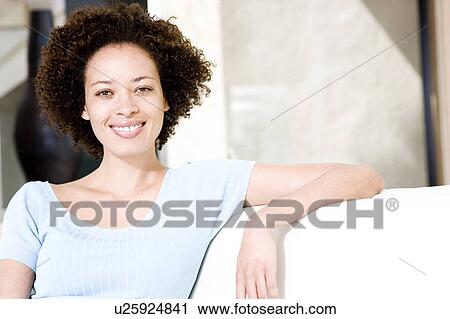 Woman relaxing on a sofa, smiling View Large Photo Image Stock Image - Woman relaxing on a sofa, smiling. Fotosearch