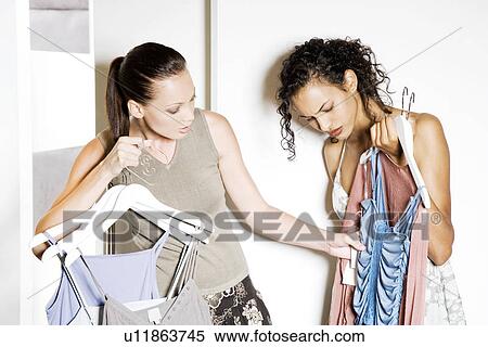 Two friends outside the changing room of a shop, waiting to try on clothes View Large Photo Image Stock Photography - Two friends outside the changing room of a shop, waiting to try on clothes. Fotosearch
