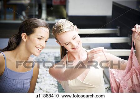 Two women sitting outside looking at pretty clothes they've just purchased View Large Photo Image Stock Image - Two women sitting outside looking at pretty clothes they've just purchased. Fotosearch
