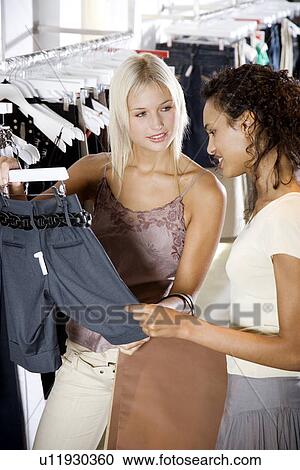 Two young women shopping for clothes View Large Photo Image Stock Image - Two young women shopping for clothes. Fotosearch