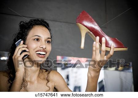 Woman buying high-heeled shoes in a shoe shop, talking on mobile phone View Large Photo Image Stock Image - Woman buying high-heeled shoes in a shoe shop, talking on mobile phone. Fotosearch