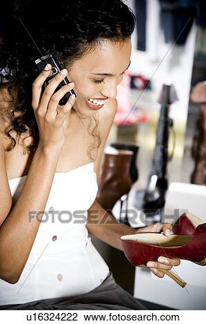 Woman buying high-heeled shoes in a shoe shop, talking on mobile phone View Large Photo Image Stock Image - Woman buying high-heeled shoes in a shoe shop, talking on mobile phone. Fotosearch