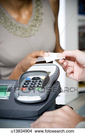 Picture - Woman taking credit card and receipt from sales assistant. Fotosearch