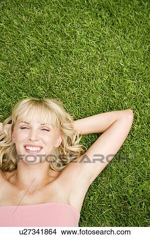 Picture - Beauty portrait of a woman laying in the grass in a tropical setting.. Fotosearch