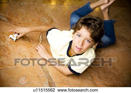 Stock Image - Latino boy playing with toy car on floor. Fotosearch