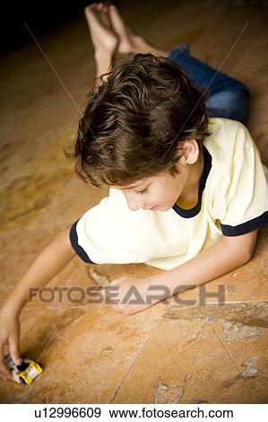 Latino boy playing with toy car on floor View Large Photo Image Stock Photo - Latino boy playing with toy car on floor. Fotosearch