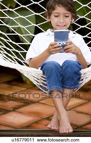 little boy playing electronic game sitting in hammock View Large Photo Image Stock Image - little boy playing electronic game sitting in hammock. Fotosearch
