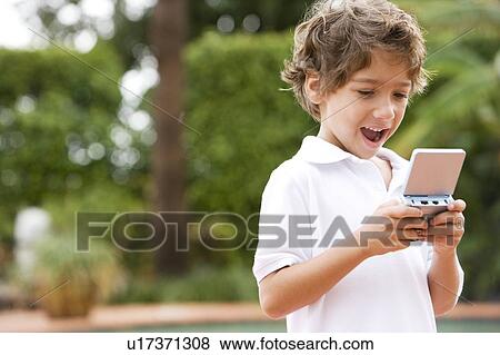 Stock Photo - little boy playing with hand held computer game. Fotosearch