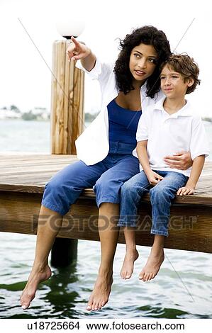 mother and son sitting on jetty looking out to sea View Large Photo Image Picture - mother and son sitting on jetty looking out to sea. Fotosearch