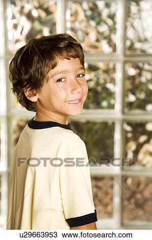 Stock Image - rear view Latino boy head turned towards camera. Fotosearch
