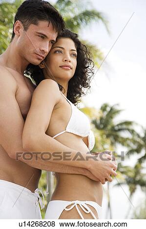 Stock Photo - Couple in swimwear on tropical holiday, drinking champagne. Fotosearch