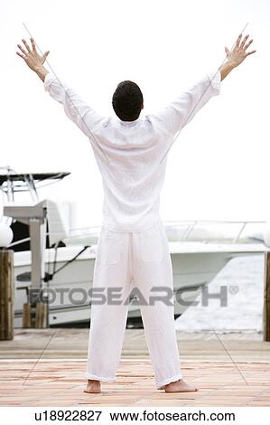 Man in white on a jetty by a boat, arms outstretched View Large Photo Image Stock Photo - Man in white on a jetty by a boat, arms outstretched. Fotosearch