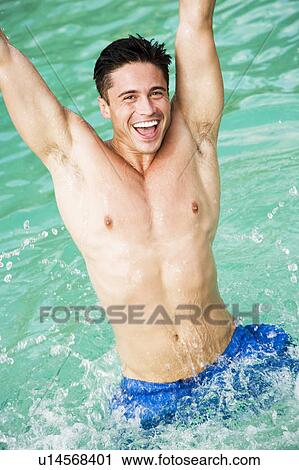 Stock Image - Man playing in a swimming pool, splashing in the water. Fotosearch