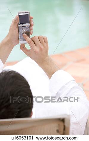 Man sitting by a swimming pool, using a mobile phone View Large Photo Image Stock Image - Man sitting by a swimming pool, using a mobile phone. Fotosearch