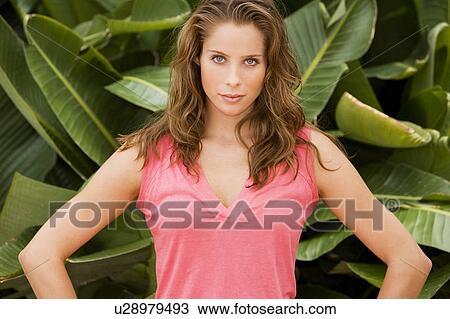 Stock Image - Portrait of woman outdoors beside tropical plant. Fotosearch