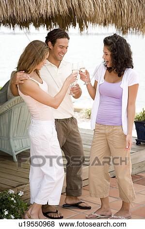 Stock Photo - Three friends at a tropical hotel bar, having a drink. Fotosearch