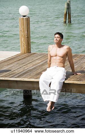 Topless man sunbathing on a jetty View Large Photo Image Picture - Topless man sunbathing on a jetty. Fotosearch
