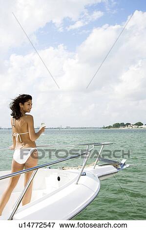 Stock Photo - Woman in a white bikini standing on a yacht on the sea. Fotosearch