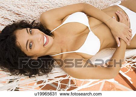 Woman lying in a hammock in the sun, wearing a white bikini View Large Photo Image Stock Image - Woman lying in a hammock in the sun, wearing a white bikini. Fotosearch