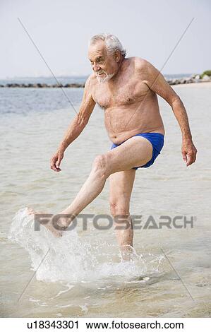 Stock Image - Portrait of a senior man in swimming trunks at the beach . Fotosearch