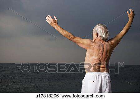 Portrait of a senior man looking out to sea with his arms outstretched View Large Photo Image Stock Photograph - Portrait of a senior man looking out to sea with his arms outstretched . Fotosearch