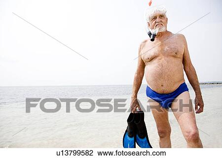 Stock Image - Senior man with snorkel gear and flippers at the beach . Fotosearch